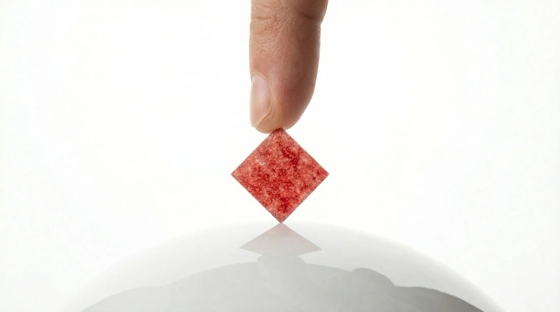 One square dissolvable NRGStrip held above a clean white surface